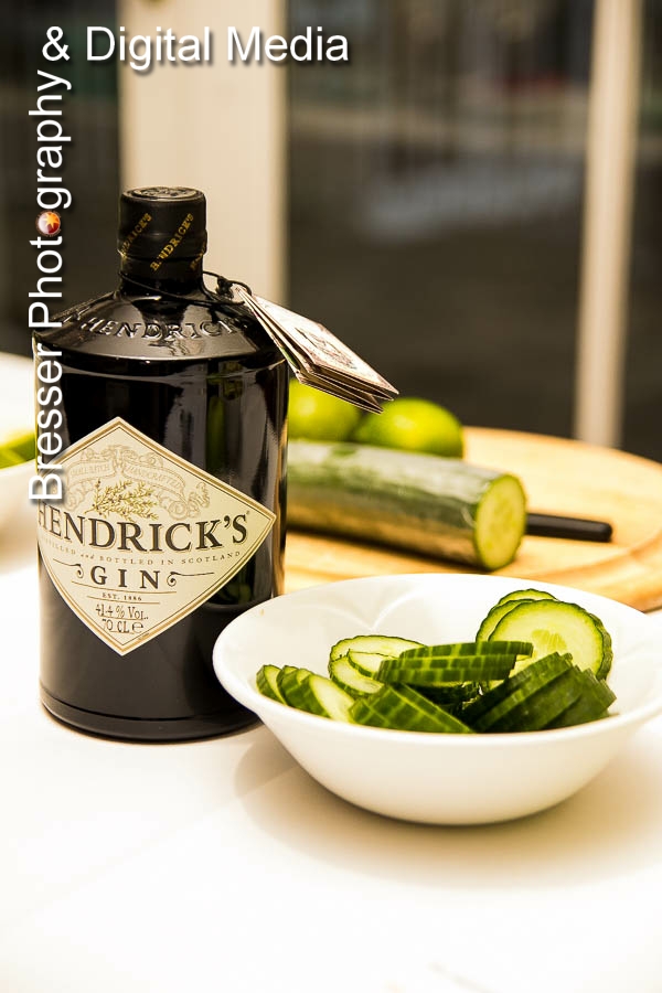 Bottle of Hendrick's gin with bowel of slivers of cucumber and cucumber in the background on a cutting board 