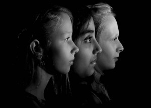 black and white head shot portrait of three children in profile