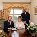 Formal pose of bride, groom and witnesses at a table