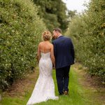 Wedding couple walking away down an avenue of trees