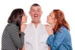 Middle aged man with two young women; his daughters, on his shoulders