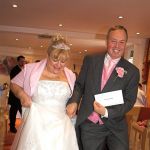 Newly married couple leave the ceremony with their marriage certificate on display