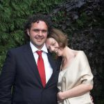 bride and groom stant together with a shrub backdrop