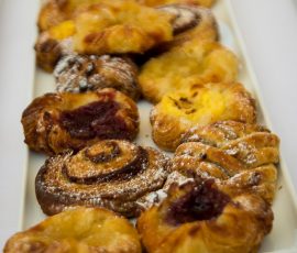A close up of a plate of pastries lightly dusted with icing sugar.