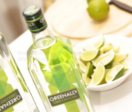 Bottle of Greenhall's gin taken at a Dutch tilt angle with wedges of lime in a bowl nearby