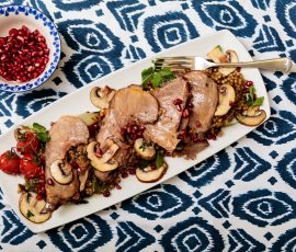 Mediterranean lamb served with pomegranate resting of a tablecloth with rustic blue pattern