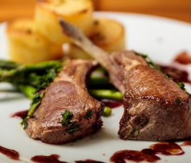 Close up of a plate of lamb chops, potatoes and asparagus