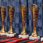 Six gold coloured trophies lined up ready to hand out