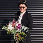 Steampunk bride with flowers poses in front of a black metal door