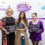 Three women holding awards from a corporate awards event