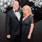 Smartly dressed couple pose for a formal portrait at a corporate charity event