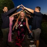 Woman CEO walks through an arch of her colleagues' arms at night